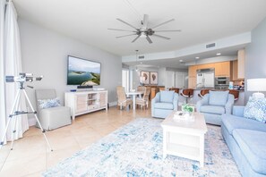 Un saló modern amb televisió de pantalla plana, ventilador de sostre i zona de menjador amb mobles de vímet.