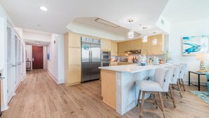 Eine moderne Küche mit Holzausstattung, einem Edelstahlkühlschrank und einer zentralen Kochinsel mit Barhocker.