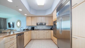 A modern kitchen with light wooden cabinets, stainless steel appliances, and a tiled backsplash. - Charming Beachy Condo Overlooking Perdido Bay and Gulf of Mexico~ Complimentary Boat Slip! (Orange Beach)