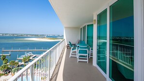 Un balcón con vista al océano y un muelle. Hay dos sillas y una mesa en el balcón.