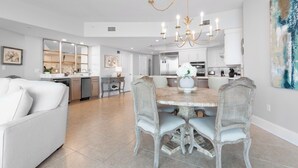 A modern kitchen with white cabinets, a dining table with chairs, and a chandelier. - Upscale Beach Condo Overlooking Robinson Island and Docks (Orange Beach)