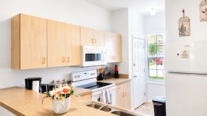 A modern kitchen with wooden cabinets, a built-in microwave, a stove, and a refrigerator. - Resort Villa, Pools Fun and relaxation/w Kingbed. (Kissimmee)