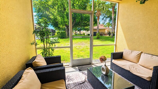A room with wicker furniture, a glass coffee table, and a view of a green lawn and trees. - Resort Villa, Pools Fun and relaxation/w Kingbed. (Kissimmee)