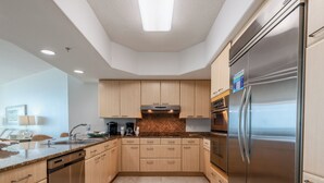 Una cocina moderna con armarios de madera clara, un refrigerador de acero inoxidable y un horno empotrado.
