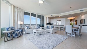 Un salón amplio con un gran ventanal, un ventilador de techo y una zona de comedor con mesa y sillas.