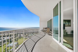 Ein Balkon mit gebogener Geländer, mit Blick auf Strand und Poolbereich.
