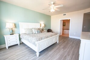 A bedroom with a bed, nightstands, a ceiling fan, and a bathroom visible through an open door. - Four Bedroom Unit with Views of the Pool Area and Lazy River Deck. Complimentary Boat Slip! (Orange Beach)