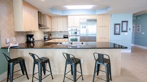 A modern kitchen with a central island, stainless steel appliances, and a light blue wall.