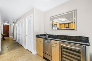 A modern kitchen with a granite countertop, stainless steel appliances, and a large mirror above the sink.