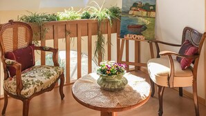 Une pièce chaleureuse avec deux chaises en bois, une petite table ronde recouverte d’une nappe en dentelle et un tableau accroché au mur.