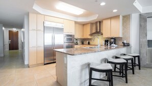Una cocina moderna con una isla central, electrodomésticos de acero inoxidable y una zona de bar con taburetes.