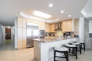 A modern kitchen with a central island, stainless steel appliances, and a bar area with stools.