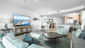 Una sala de estar moderna con televisor, sofá, mesa de centro y comedor.