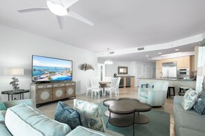 A modern living room with a TV, sofa, coffee table, and dining area.