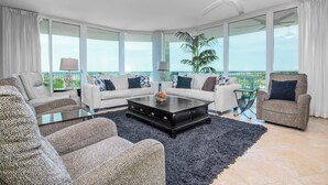 Un salón amplio con un gran ventanal, un ventilador de techo y vistas al exterior.