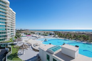 Un complexe hôtelier doté d’une grande piscine, de nombreux balcons et offrant une vue sur la plage.