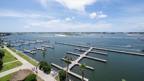 A marina with multiple docks and boats, a clear sky, and a distant bridge. - Cozy Two Bedroom Waterfront Condo with Large Balcony! Complimentary Boat Slip! (Orange Beach)