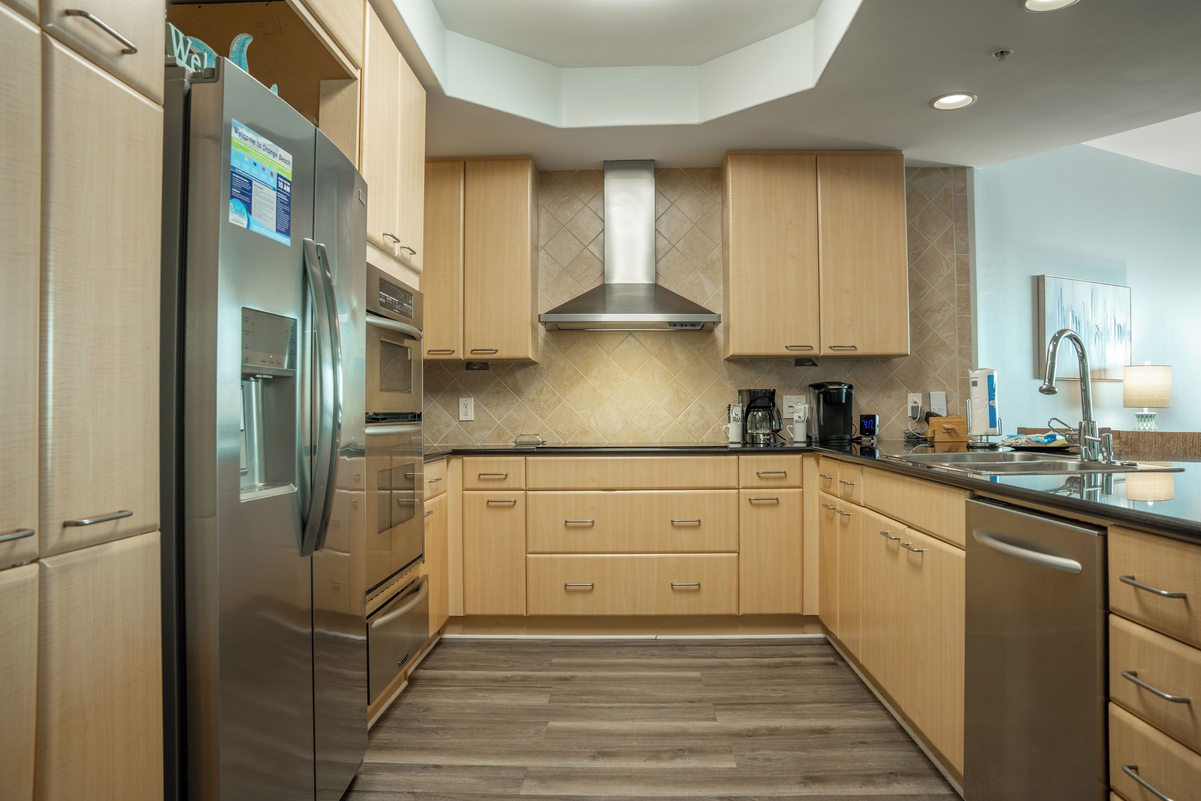 Una cocina moderna con armarios de madera, electrodomésticos de acero inoxidable y salpicadero de azulejos.