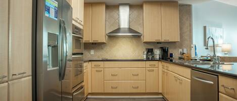 Una cocina moderna con armarios de madera, electrodomésticos de acero inoxidable y salpicadero de azulejos.