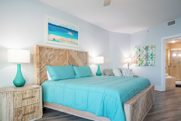 Une chambre à coucher comprenant un lit, deux tables de chevet, une tête de lit, un tableau et un espace douche.