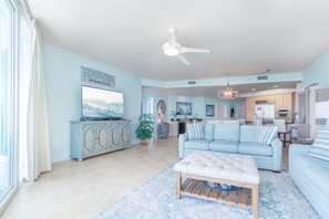 A spacious living room with a large TV, a ceiling fan, and a dining area with a chandelier.