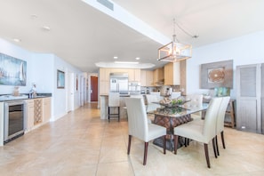 A spacious kitchen with modern appliances, a dining area with a glass table, and a view of the living area.