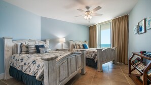 A bedroom with two beds, a ceiling fan, a window with curtains, and a bookshelf. - Updated Family-Friendly Condo with Media Room and Wraparound Balcony. Complimentary Boat Slip! (Orange Beach)