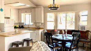 Une cuisine compacte dotée d’un îlot central, d’un coin repas avec des chaises en bois et d ’un lustre.