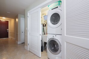 A laundry room with two stacked front-loading washing machines and a dryer. - Cozy Two Bedroom Condo. Complimentary Boat Slip! (Orange Beach)