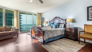 Ein Schlafzimmer mit einem großen Bett, einem Deckenventilator, einem Nachttisch, einem Sessel und Blick ins Freie.