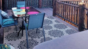 Een houten blokhut met een patio, inclusief een tafel en stoelen, een overdekte zithoek en uitzicht op het omliggende landschap.