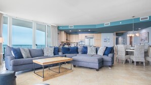 Ein modernes Wohnzimmer mit einer Eckcouch, einem Holztisch und einem Essbereich mit Korbstühlen.