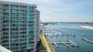 Ein Hochhaus-Hotel mit mehreren Balkonen mit Blick auf eine Marina mit Booten und einem Strand.