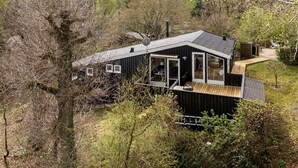 A modern cabin with a deck, large windows, and a chimney. - 3 bedroom awesome home in Glesborg (Glesborg)
