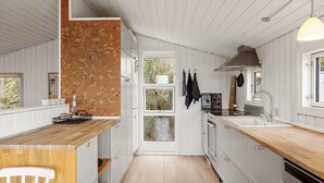 A compact kitchen with white cabinetry, a wooden countertop, and a cork wall. - 3 bedroom awesome home in Glesborg (Glesborg)