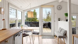 A modern kitchen with a wooden countertop, a dining area with a table and chairs, a bench, and a large window with a view of the outdoors. - 3 bedroom awesome home in Glesborg (Glesborg)