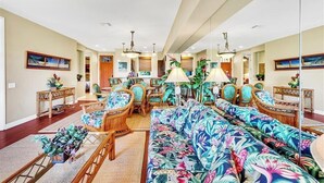 A spacious living room with a large sofa, wicker chairs, and a dining area. - Island Therapy - Walk to A-Bay, Shops & Dining - Golf Views - Sleeps 6 (Waikoloa)