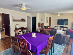 A dining area with a purple tablecloth, wooden chairs, a ceiling fan, and a television in the background. - Canyon House near Yellowstone  (Gardiner)