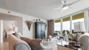 A modern living room with a grey sofa, a coffee table, and a ceiling fan.