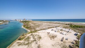 Une zone côtière comprenant une plage, un port de plaisance et un parking avec des véhicules.