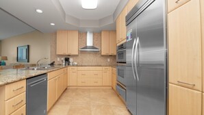 Une cuisine moderne avec des meubles en bois clair, des appareils en acier inoxydable et un dosseret carrelé.
