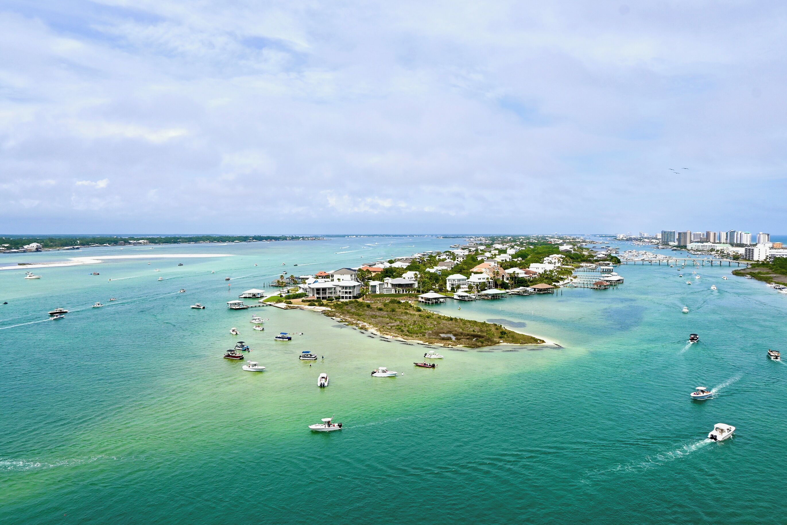 An aerial view of a coastal area with boats, a marina, and buildings.
