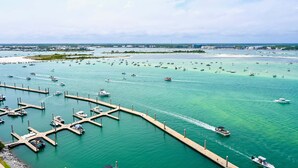 Un port de plaisance avec des bateaux amarrés aux quais, un quai s’étendant dans l’eau et une côte lointaine parsemée de bâtiments.