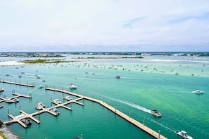 Un puerto deportivo con barcos amarrados en muelles, un muelle que se adentra en el agua y una costa distante con edificios.