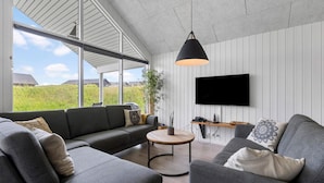 A modern living room with a sectional sofa, a round coffee table, and a mounted TV. - Nice home in Sydals with sauna (Sydals)