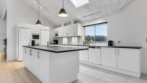 A modern kitchen with white cabinetry, a large island, and a skylight. - Nice home in Sydals with sauna (Sydals)