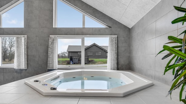 A modern bathroom with a freestanding bathtub, large windows, and a view of a house. - Nice home in Sydals with sauna (Sydals)