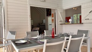 A dining area with a table set for four, surrounded by white chairs with grey cushions. - Beautiful villa with sea view and infinity pool (Saint François)