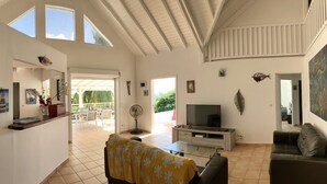 A spacious living area with a TV, sofa, and dining area visible. - Beautiful villa with sea view and infinity pool (Saint François)