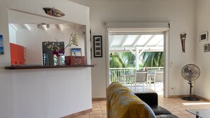 A living room with a sofa, a coffee table, a fan, and a view of a balcony with outdoor furniture. - Beautiful villa with sea view and infinity pool (Saint François)